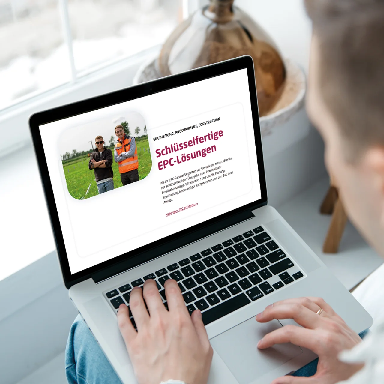 Blick über die Schulter einer Person auf einen Laptop, der eine Website zu „Schlüsselfertige EPC-Lösungen“ anzeigt.