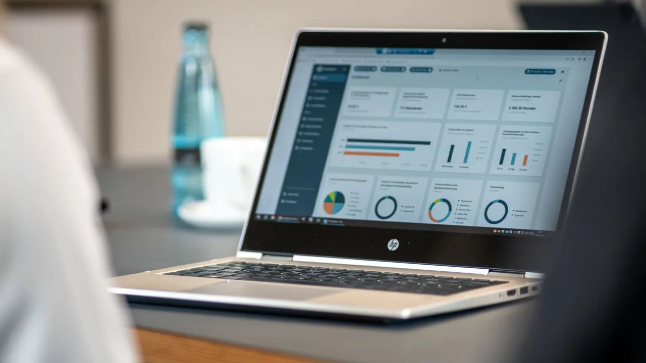Ein geöffneter Laptop auf einem Schreibtisch zeigt ein Dashboard mit verschiedenen Diagrammen und Analysen.