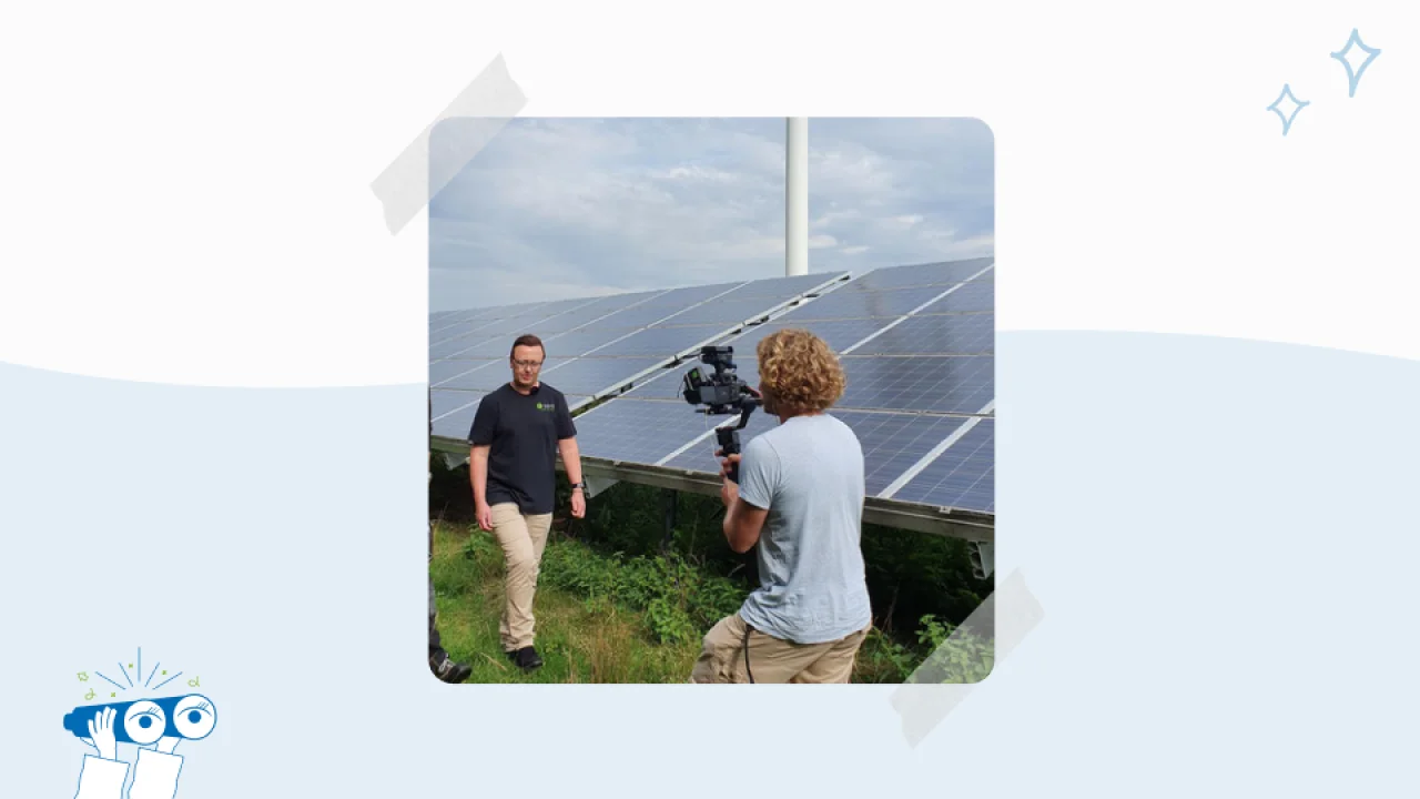 Ein Kameramann filmt einen Mann vor einer Solaranlage im Freien.