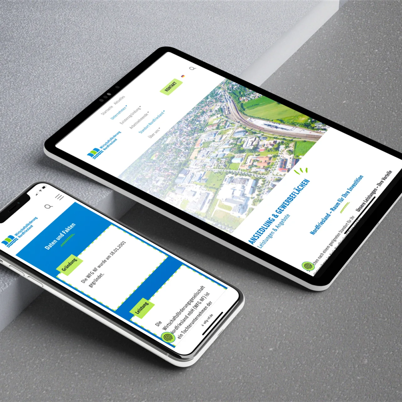 Smartphone und Tablet auf grauem Grund zeigen die Website der Wirtschaftsförderung Nordfriesland.
